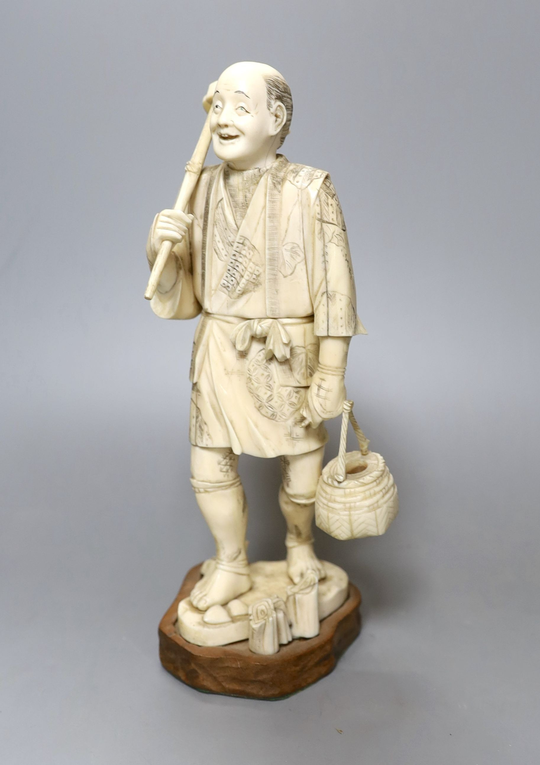 A Japanese carved and engraved ivory figure of a farmer, Meiji-period, on plinth, 25cm